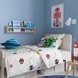 Quarto infantil com edredom AFTONSPARV, planetas, estrelas, parede azul, estante, pôster de robô vermelho, travesseiro planeta azul, brinquedo verde, lâmpada de foguete vermelha.