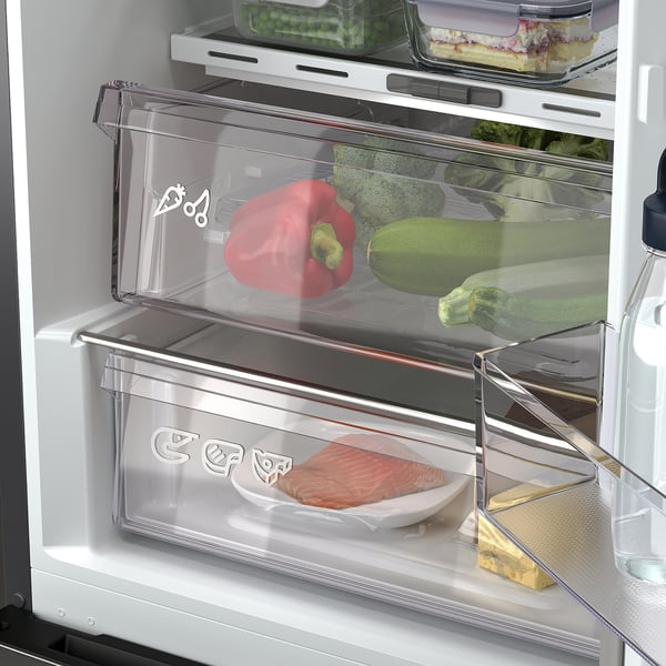 Geladeira moderna com alças escondidas elegantes, mostrando gaveta mais crocante com pimenta vermelha, courgette e brócolis, destacando o controle de umidade.