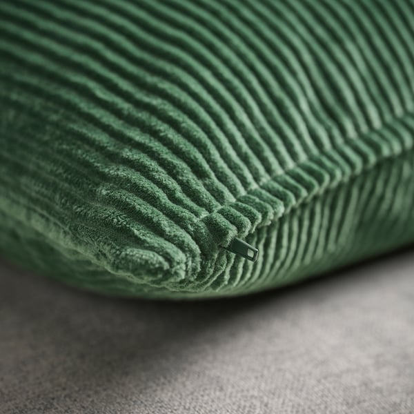 Almofada de veludo cotelê verde em plano próximo, fecho escondido, textura macia.