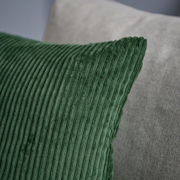 Capa de almofada em veludo cotelê verde-escuro, macia e durável, com um padrão às riscas subtil.