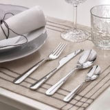 Talheres elegantes colocados em uma mesa. Inclui garfo, faca e colheres, dispostos ordenadamente para o jantar.