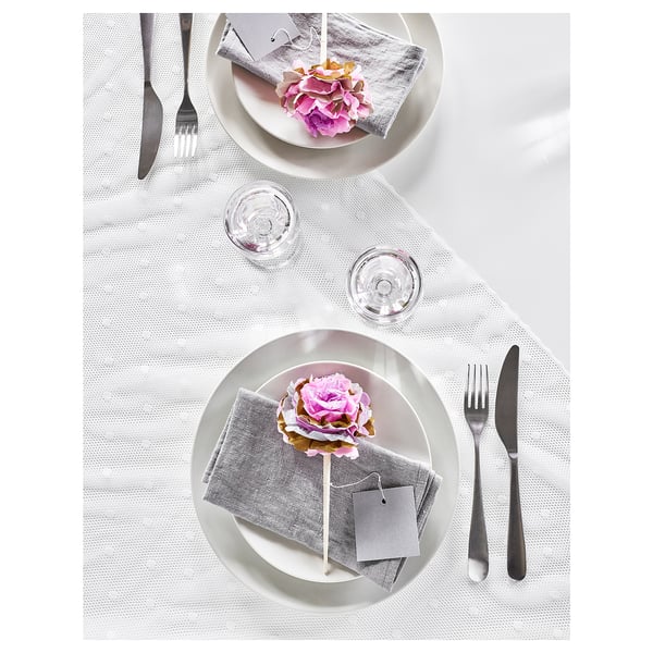 Mesa elegante com pratos brancos, guardanapos cinza, decoração de flores rosa, copos transparentes e talheres de prata BEHAGFULL.
