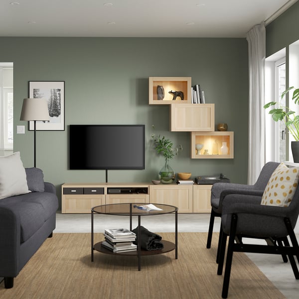 Sala de estar moderna com paredes de sálvia, módulo BESTÅ, sofá cinzento e plantas.