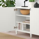 Módulo de arrumação BESTÅ branco com prateleiras reguláveis. A prateleira superior exibe uma tigela de madeira. A prateleira inferior comporta livros, bandeja e cesta.