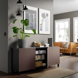 Uma sala de estar moderna com um aparador BESTÅ com prateleiras reguláveis, armazenamento de livros e uma planta.