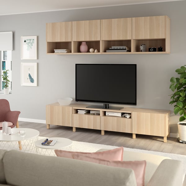 Sala de estar moderna com TV de tela plana, centro de entretenimento de madeira, paredes cinza, arte, assentos aconchegantes e plantas.