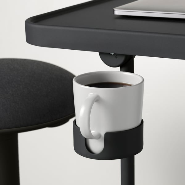 Suporte para laptop preto com inclinação e altura ajustáveis. Inclui um porta-copos destacável segurando uma caneca branca com café.