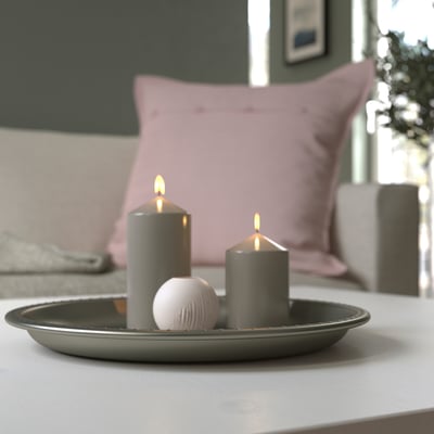 Prato de vela cinza com duas velas acesas e uma pedra decorativa, realçando o ambiente do quarto.