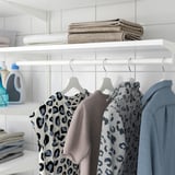 Armário arrumado com roupas, toalhas e detergente.