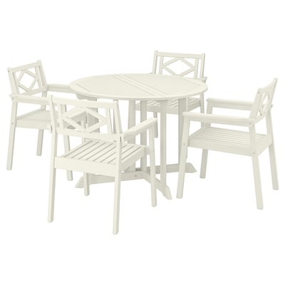 Um conjunto de cadeiras de exterior BONDHOLMEN em branco. Inclui uma mesa redonda e quatro poltronas com um design clássico de madeira.