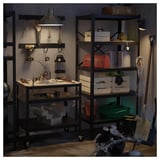 Um sistema de armazenamento de metal preto BROR com prateleiras e uma bancada de trabalho, segurando ferramentas e suprimentos em uma garagem.