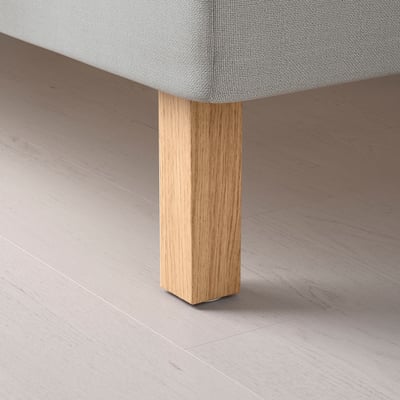 Uma perna de mesa de madeira com acabamento natural apresentando textura de grão fino e revestimento de laca acrílica lisa e transparente.
