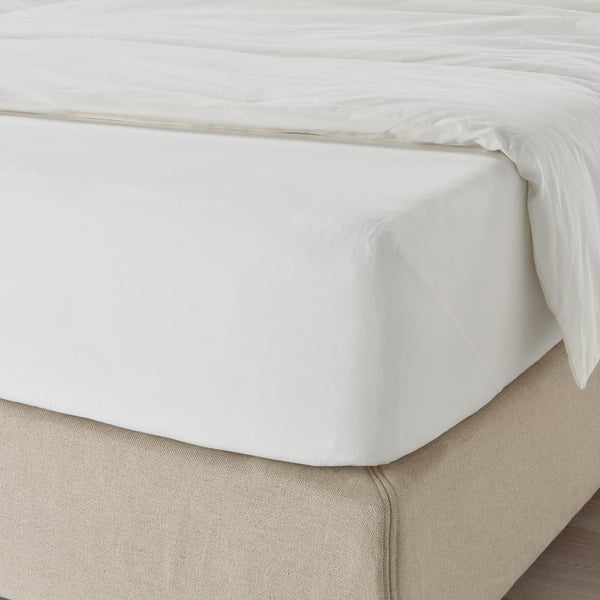 Lençol branco nítido na cama, com bordas elásticas que garantem um ajuste confortável, ideal para colchões de 26 cm.