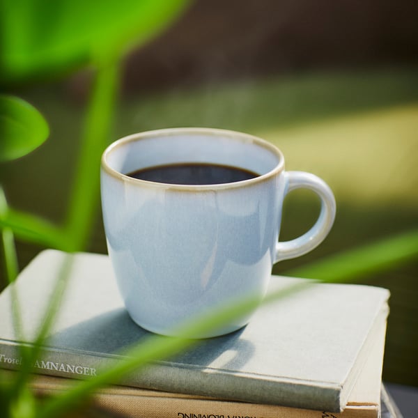 Caneca branca com café em livros. Design simples e artesanal.