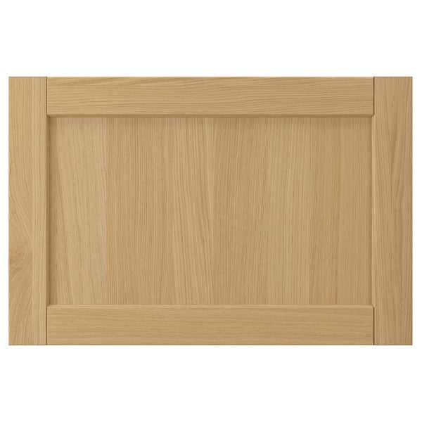 Esta imagem mostra uma porta de armário FORSBACKA castanho claro feita de chapa de carvalho, com um design de moldura clássico com rebordos biselados.