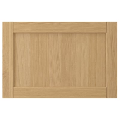 Esta imagem mostra uma porta de armário FORSBACKA castanho claro feita de chapa de carvalho, com um design de moldura clássico com rebordos biselados.