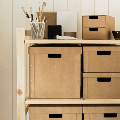 Caixas de armazenamento GÄRDESGÅRD em cartão castanho, resistentes e manuseadas, empilhadas ordenadamente. Caber vários itens e fácil de transportar.