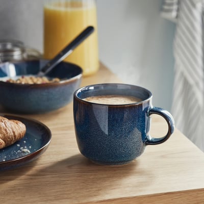 Caneca de grés azul oceano com alça, acabamento em esmalte reativo, formato redondo.