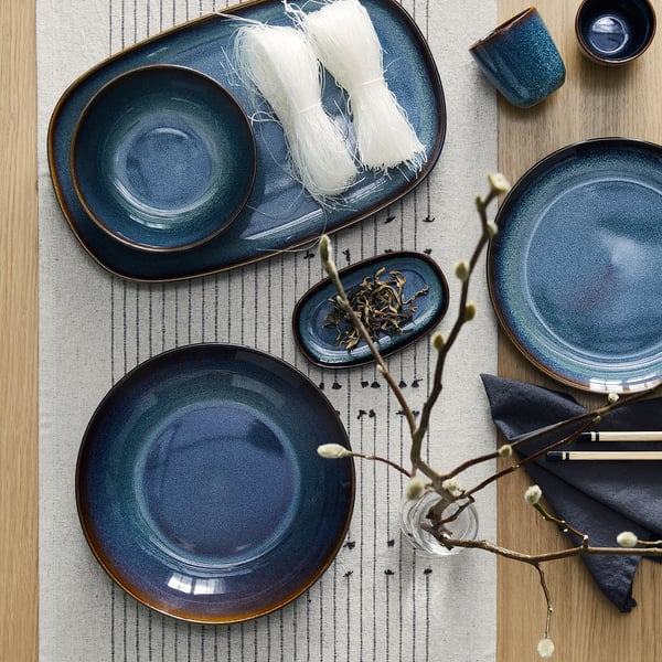 GLADELIG pratos de grés azul-oceano com acabamentos, em passadiça às riscas com alimentos.