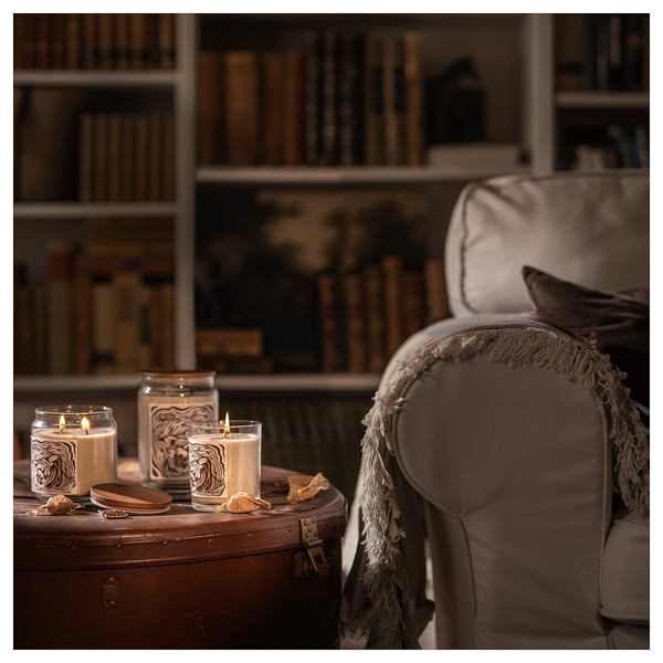 Sala de estar aconchegante com poltrona, velas e estante.