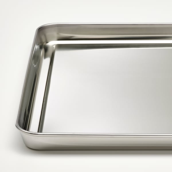 Bandeja de aço inoxidável, elegante e polida, ideal para servir pratos grelhados.