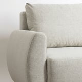 Sofá moderno em tecido cinza claro, apresentando linhas limpas e estofamento robusto. O close-up destaca o apoio de braço e o encosto confortáveis e arredondados.