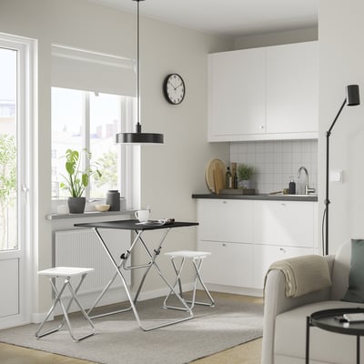 Cozinha moderna com mesa dobrável GUNDE, decoração branca e relógio preto.