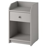 Uma mesa de cabeceira HAUGA cinza com uma gaveta e duas prateleiras abertas. É um design moderno e minimalista, adequado para várias configurações de quarto.