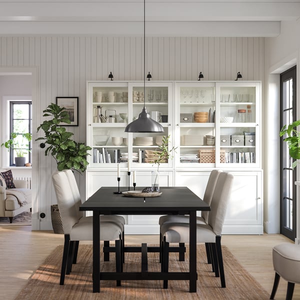 Sala de jantar moderna com aparador HAVSTA branco, mesa de jantar preta, cadeiras cinzentas e pendente.