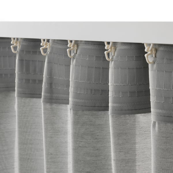 Cortinas cinza penduradas com ganchos, oferecendo privacidade com um design texturizado e leve.