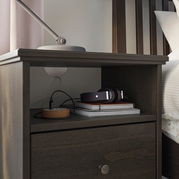 Mesa de cabeceira de madeira escura com prateleira aberta, com um fone de ouvido moderno e configuração de livros, incluindo um elegante organizador de arame.