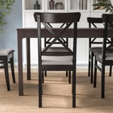 Conjunto de jantar com cadeiras de madeira escura e assentos almofadados, ideal para longas refeições e conversas.