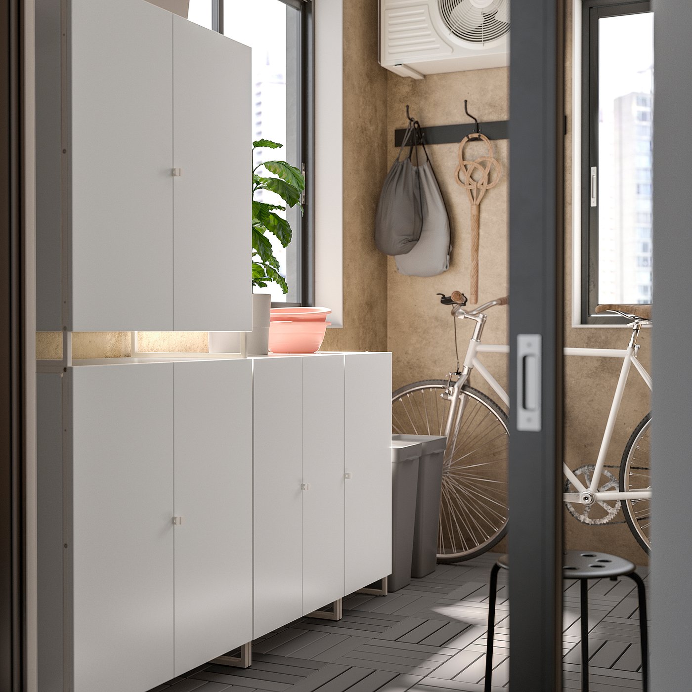 Quarto moderno com armários de arrumação JOSTEIN brancos, um vaso de plantas, sacos suspensos e uma bicicleta branca.