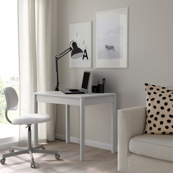 Mesa branca com laptop, artigos de papelaria e decoração.