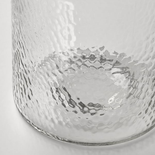 Vaso de vidro transparente com superfície texturizada, semelhante a bolha, capturado em close-up.