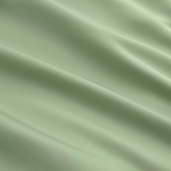 Capa de edredão verde lisa e lustrosa, finamente tecida a partir de liocel, exibindo dobras elegantes.