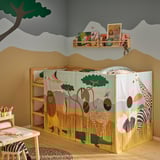 Quarto infantil com cama KURA, cortinas com tema de safári, cadeira zebra e prateleiras de brinquedos.