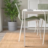 Uma cadeira de escritório leve e empilhável chamada LÄKTARE com uma capa de tecido verde e pernas de plástico, concebida para facilitar a limpeza e poupar espaço.