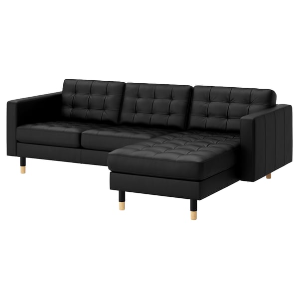 Sofá em couro preto em forma de l, encosto e assento tufted, pernas de madeira.