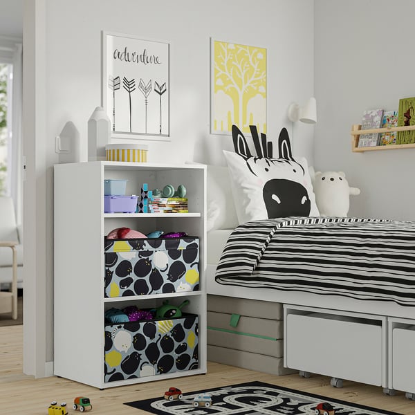Quarto das crianças com arrumação para brinquedos LASTARE , roupa de cama zebra, tapete preto/branco, arte colorida e carrinho de brinquedo de madeira.