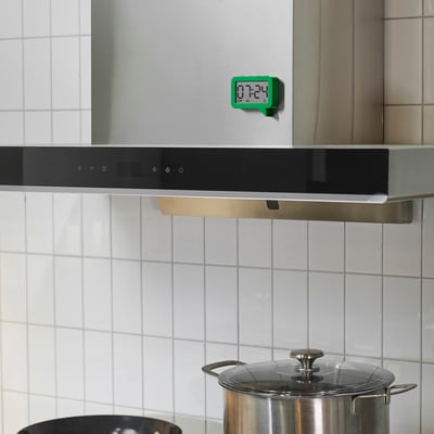 Íman verde de relógio de cozinha com temporizador na parede de azulejo.