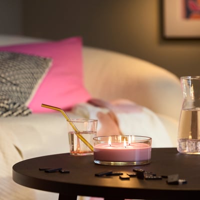 Quarto acolhedor com vela cor-de-rosa LOTSFÅGEL , vidro com palha dourada e garrafa.