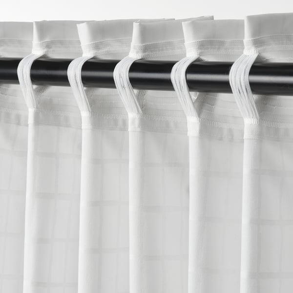 Varão de cortina preto com cortinas de grade branca transparente, equilibrando luz e privacidade.