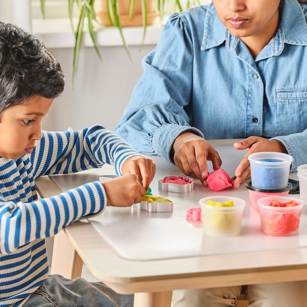 Duas pessoas brincando com massa de modelar colorida e cortadores de biscoitos.