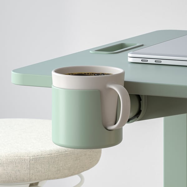 Mesa com altura ajustável, tampo inclinável e porta-copos embutido. Laptop e smartphone são colocados nele.