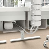 Uma mesa ajustável em altura com uma bandeja de gerenciamento de cabos e ganchos para organizar acessórios.
