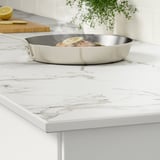 Balcão de cozinha com frigideira, rodelas de limão chiando. Superfície elegante e moderna com aparência de mármore, fácil de limpar e resistente ao calor.