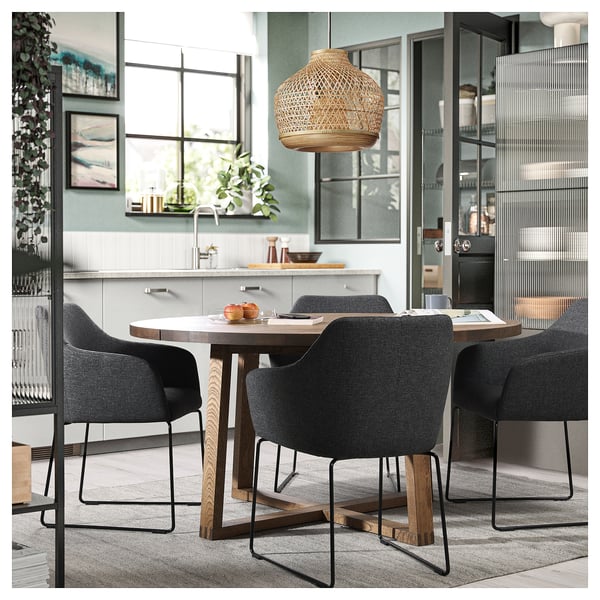 Conjunto de jantar moderno com cadeiras estofadas cinza, mesa de madeira e luminária pendente de vime.