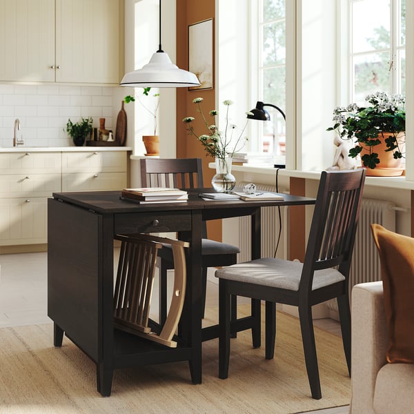 Conjunto de mesa de fazenda moderna. Madeira escura, cadeiras almofadadas, luz pendente. Tampo da mesa, plantas, lâmpada. Menores que armários.