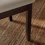 Um close-up de uma perna de cadeira elegante e robusta feita de madeira escura. Faz parte da gama de refeições NÄSINGE, conhecida pela sua qualidade e design.